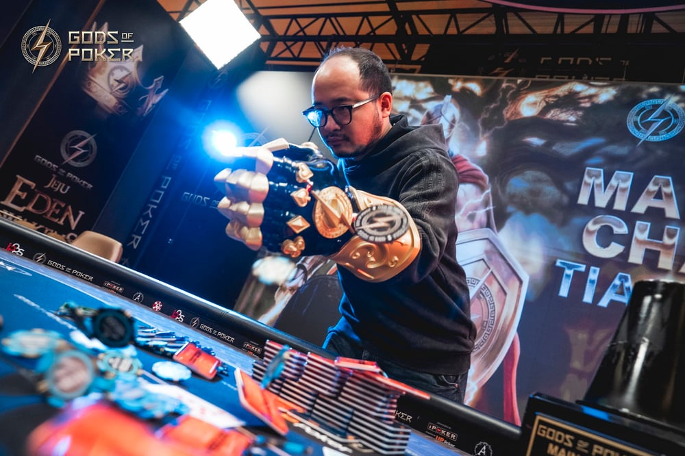 Man with glowing gauntlet plays pinball machine intently, surrounded by game art.