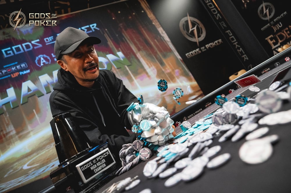 A man in a cap smiles while celebrating a poker victory, tossing chips into the air.