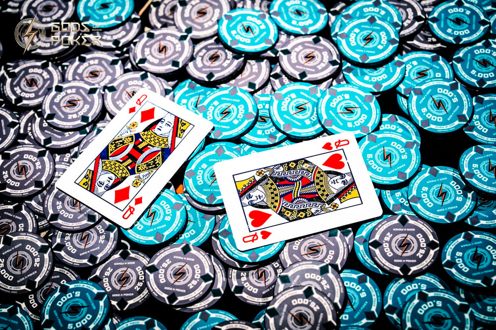 King and Queen of Hearts playing cards lie on grey and teal poker chips.